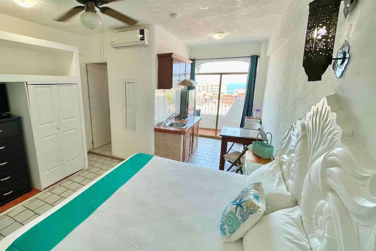 Un dormitorio con cama, escritorio y vistas al exterior.
