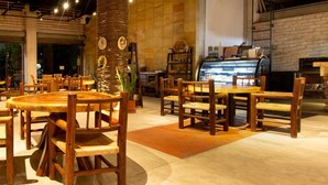A restaurant interior with wooden tables and chairs, a central pillar with artwork, and a brick wall with a counter. - Paloma Del Mar  (Puerto Vallarta)