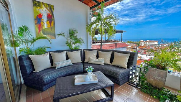 A balcony with a curved sofa, a small table with a tray, and potted plants. - Paloma Del Mar  (Puerto Vallarta)