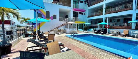 Una piscina al aire libre, sillones reclinables de piscina
