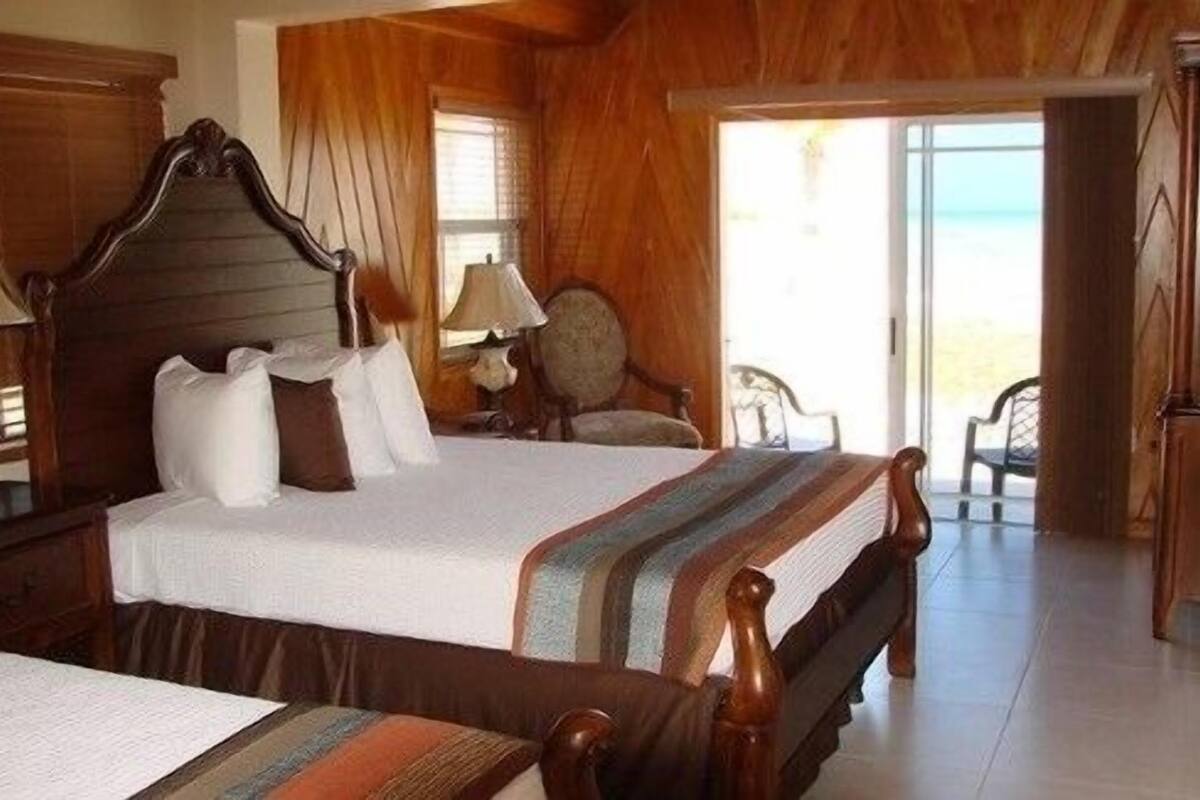 A wooden room with a bed, a chair, and a view of the outdoors.