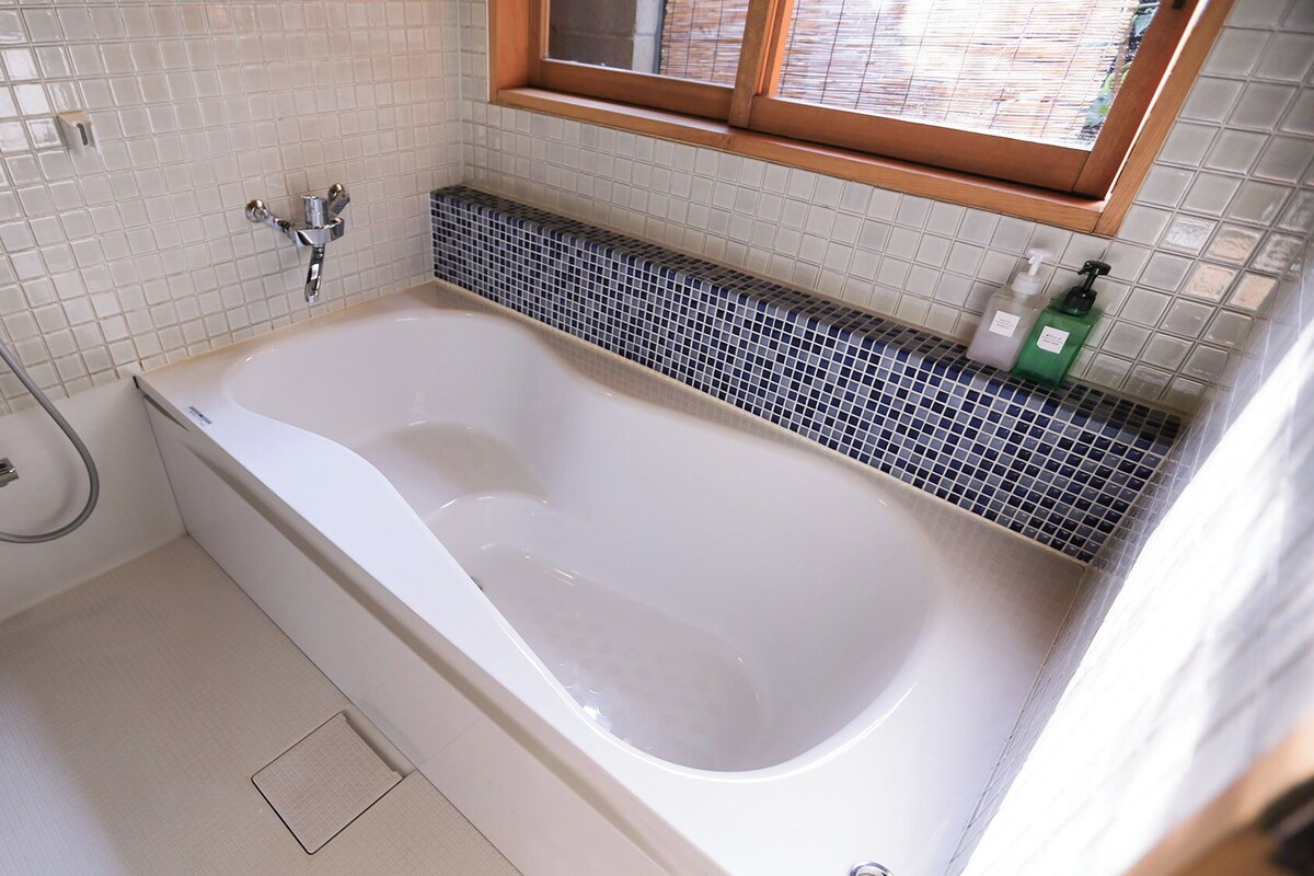 Ein Badezimmer mit Badewanne, Dusche, Toilette und einem Fenster.