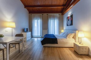 A bedroom with a bed, bedside table, lamp, and a TV on a small table. - Dalmati House (Rome)