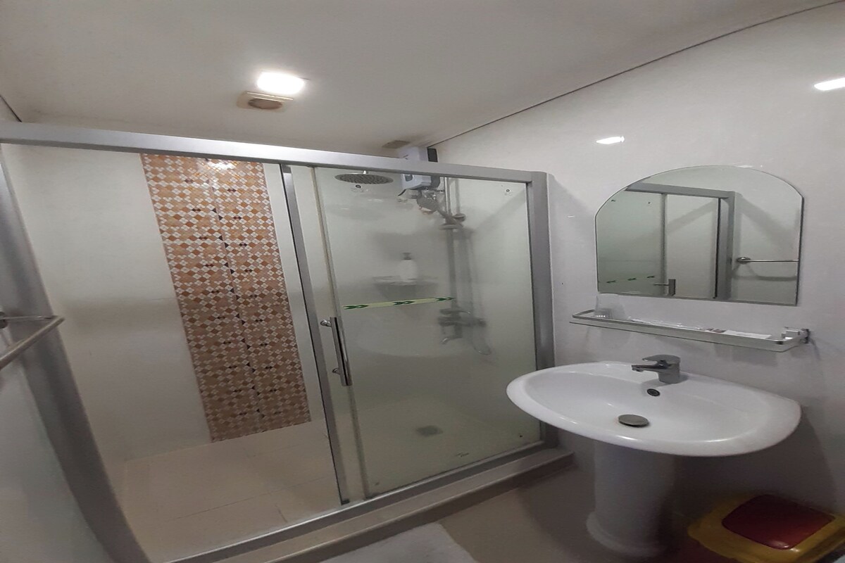 A bathroom with a glass-enclosed shower, a white sink, and a mirror above it.