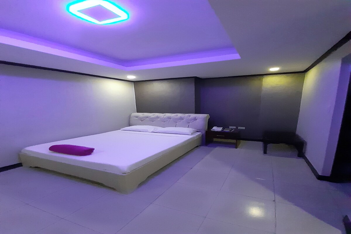 A modern bedroom with a bed, a nightstand, and a ceiling light fixture.