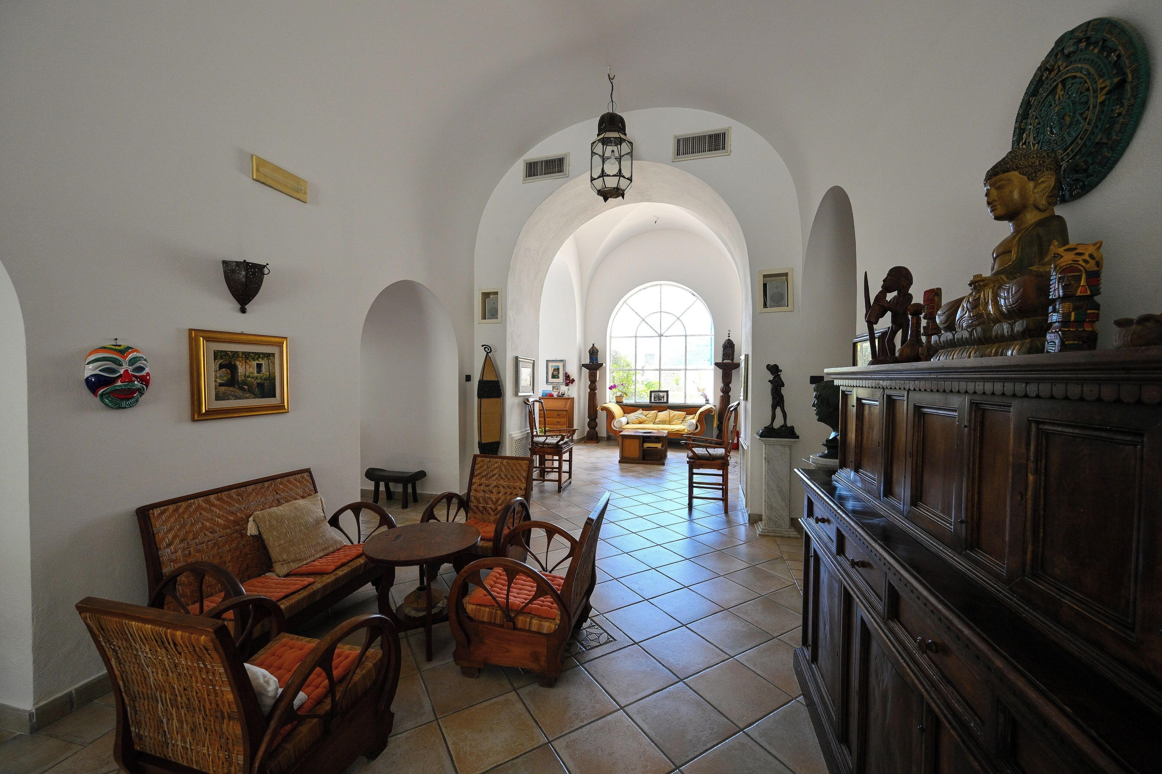 Ein geräumiger Raum mit hoher, gewölbter Decke, großem Fenster und verschiedenen Sitzmöglichkeiten, darunter eine Couch und Sessel.