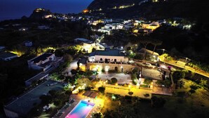 An aerial view of a resort with a swimming pool, a large building with arches, and surrounding greenery. - Villa Tara (Serrara Fontana)