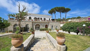 A stone building with arched windows and a central staircase leading to a balcony. - Villa Tara (Serrara Fontana)