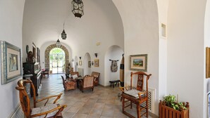 A spacious hallway with arched ceilings, wooden chairs, and a tiled floor. - Villa Tara (Serrara Fontana)