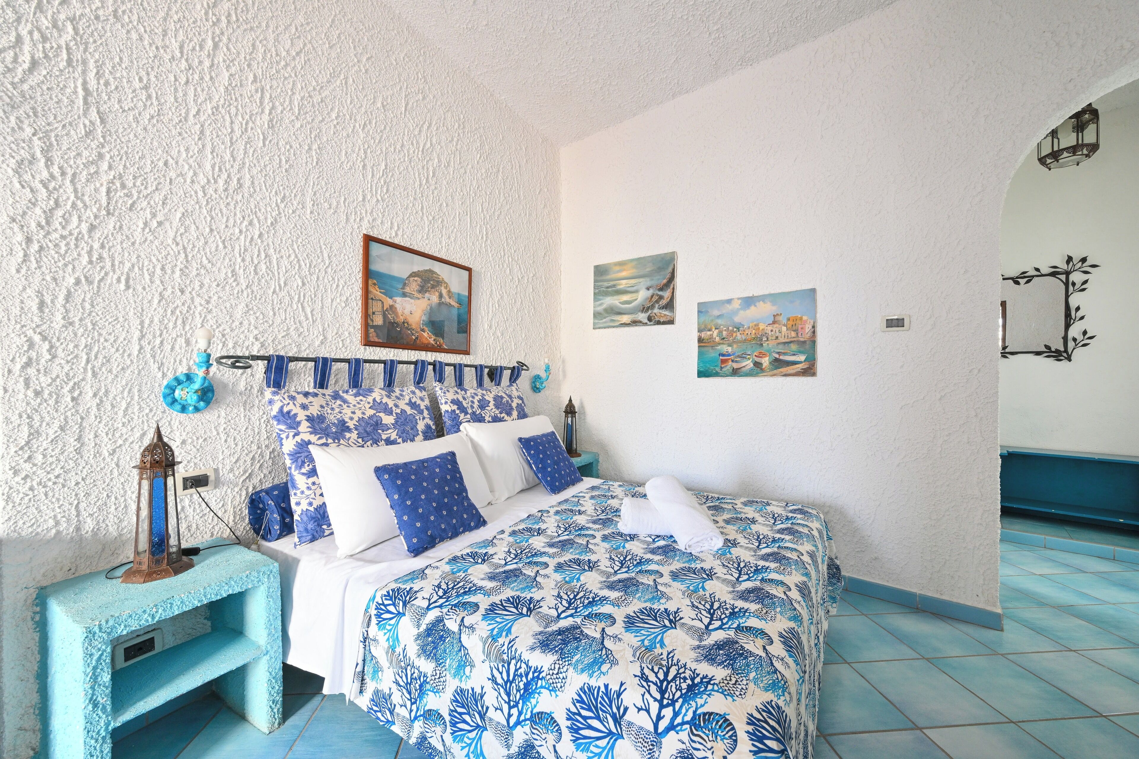 A bedroom with a bed, a nightstand, and a wall with paintings.