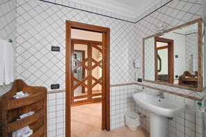 A bathroom with a wooden door, a white sink, and a mirror. - Villa Tara (Serrara Fontana)