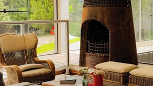 A cozy living room with a large fireplace, wicker furniture, and a view of greenery outside. - Letto Hotel Flores da Cunha (Flores da Cunha)