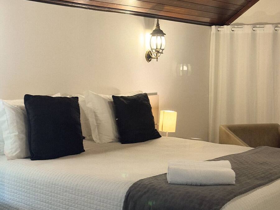 Une chambre d’hôtel avec un grand lit, une table de chevet avec une lampe et un plafond en bois.