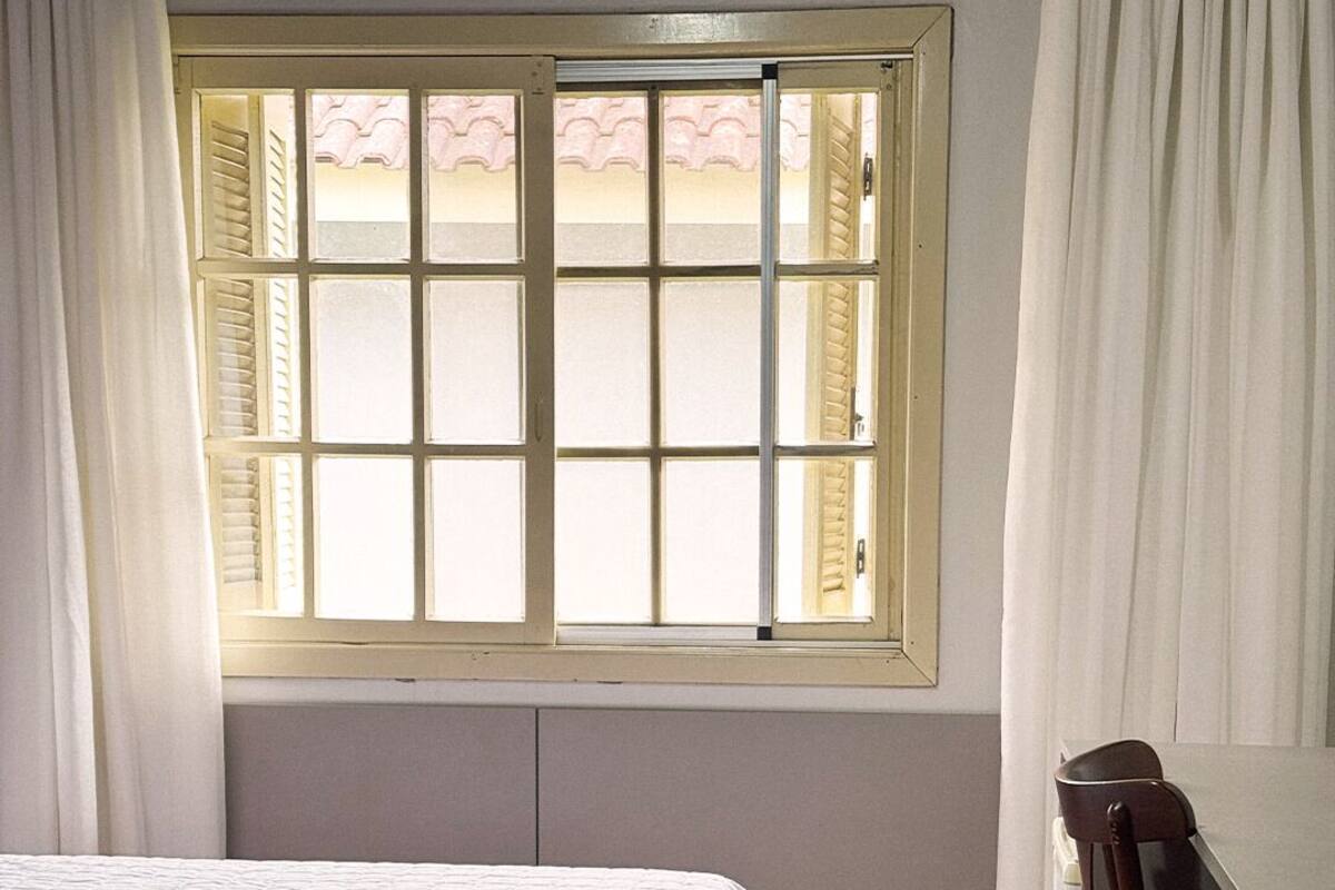 Una habitación de hotel con una cama, un escritorio y una ventana con contraventanas.