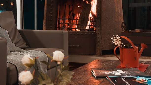 A cozy living room with a stone fireplace, a comfortable sofa, a wooden coffee table with books and a vase of flowers. - Letto Hotel Flores da Cunha (Flores da Cunha)