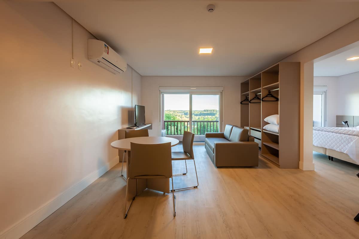 Una habitación de hotel moderna con balcón, zona de comedor y vestidor.