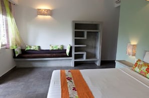 A bedroom with a bed, a bench with cushions, a wardrobe, and a wall-mounted light fixture. - The 252 (Phnom Penh)