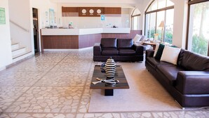 Un moderno vestíbulo de hotel con mostrador de recepción, zona de estar y una cocina al fondo.