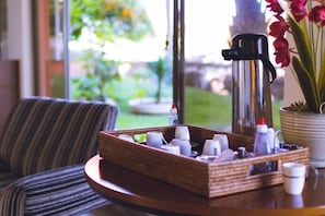 Enjoy a self-service breakfast in this serene room, featuring a coffee maker, a potted plant, and a striped chair.
