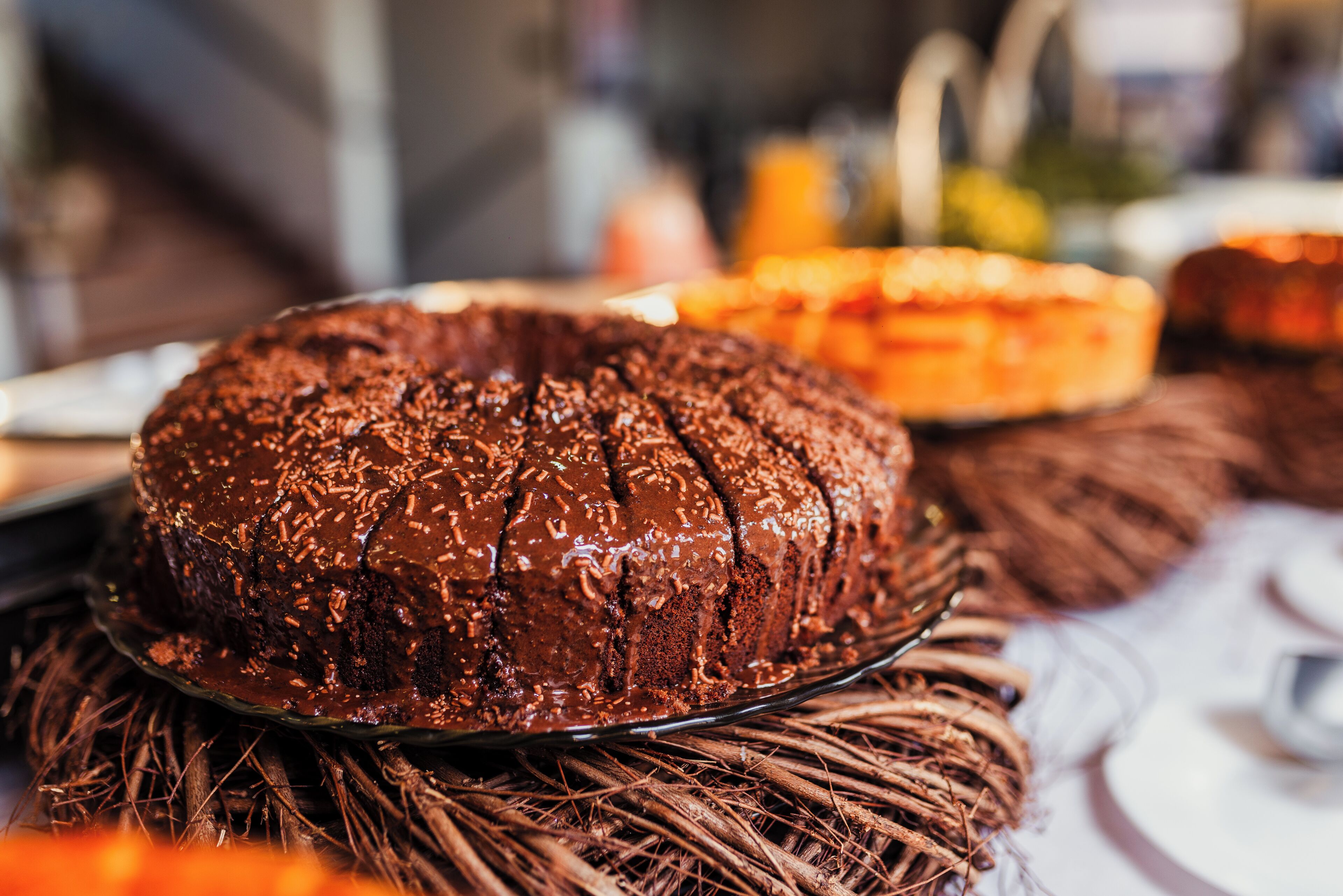 A chocolate cake on a glass plate with a decorative base.