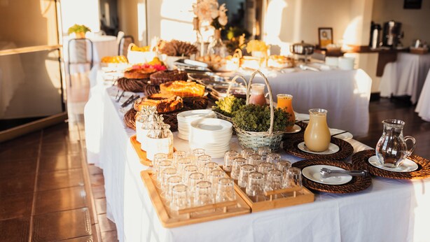 Una mesa de buffet con diferentes alimentos, cristalería y platos.
