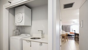 Moderni hotellihuone, jossa on pieni keittiö, sängystä avautuva kaunis näköala ja ruokailutila.