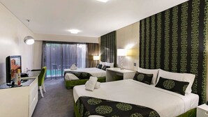 Hotellihuone, jossa on kaksi sänkyä, työpöytä, televisio ja näkymä ulos.