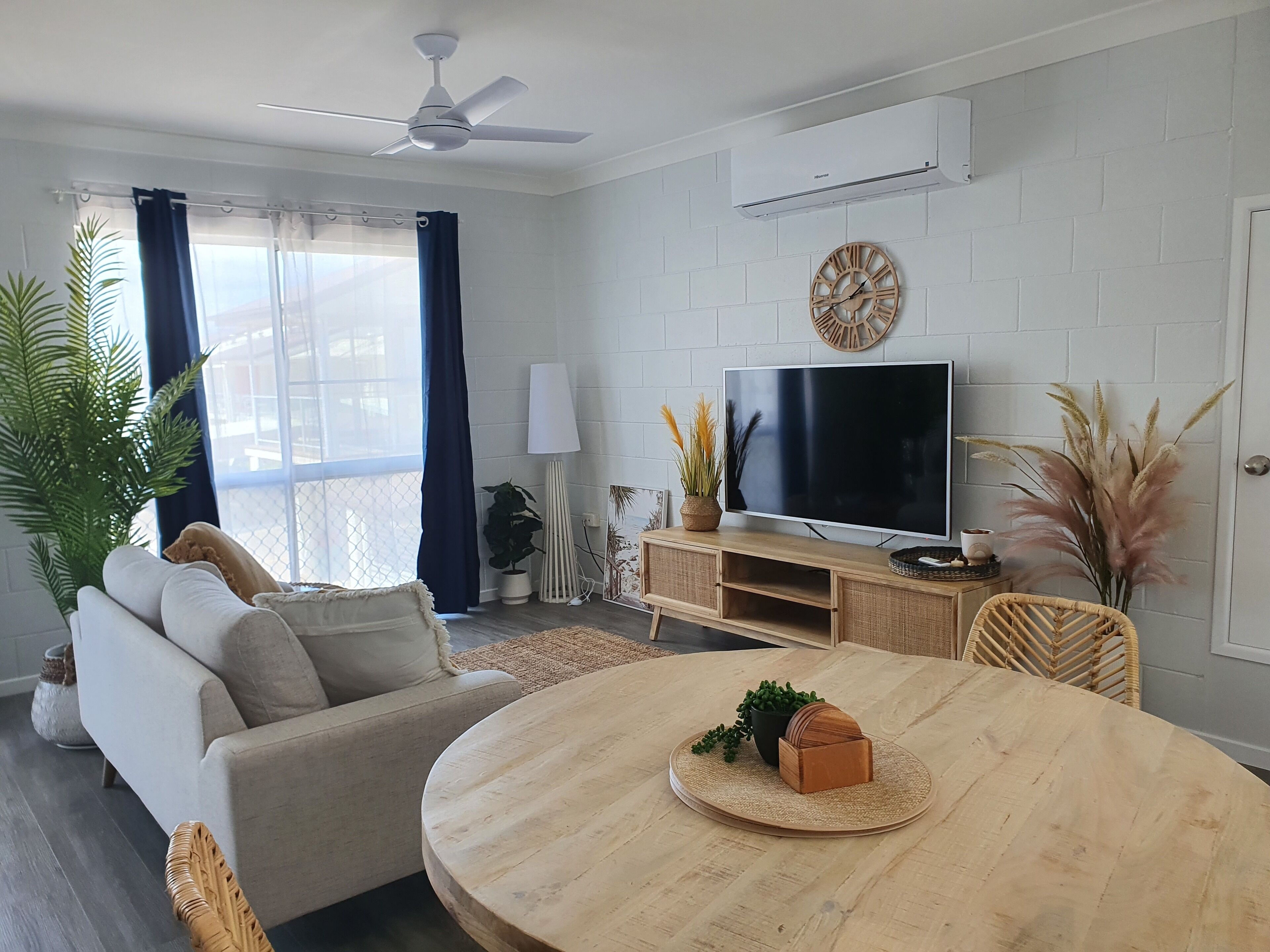 A modern living room with a sofa, TV, wooden coffee table, and decorative plants.