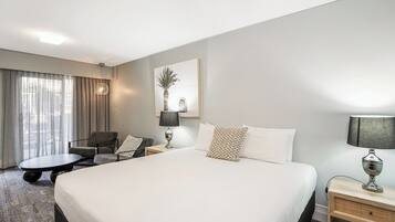 Una habitación de hotel con una cama grande, un escritorio, una silla y una lámpara.