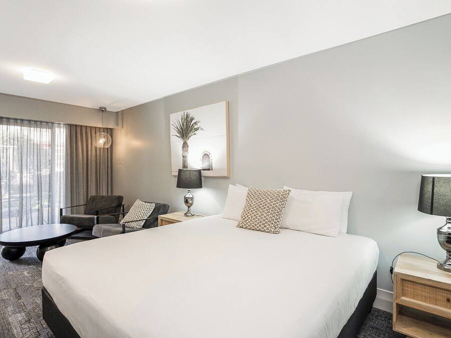 Una habitación de hotel con una cama grande, un escritorio, una silla y una lámpara.