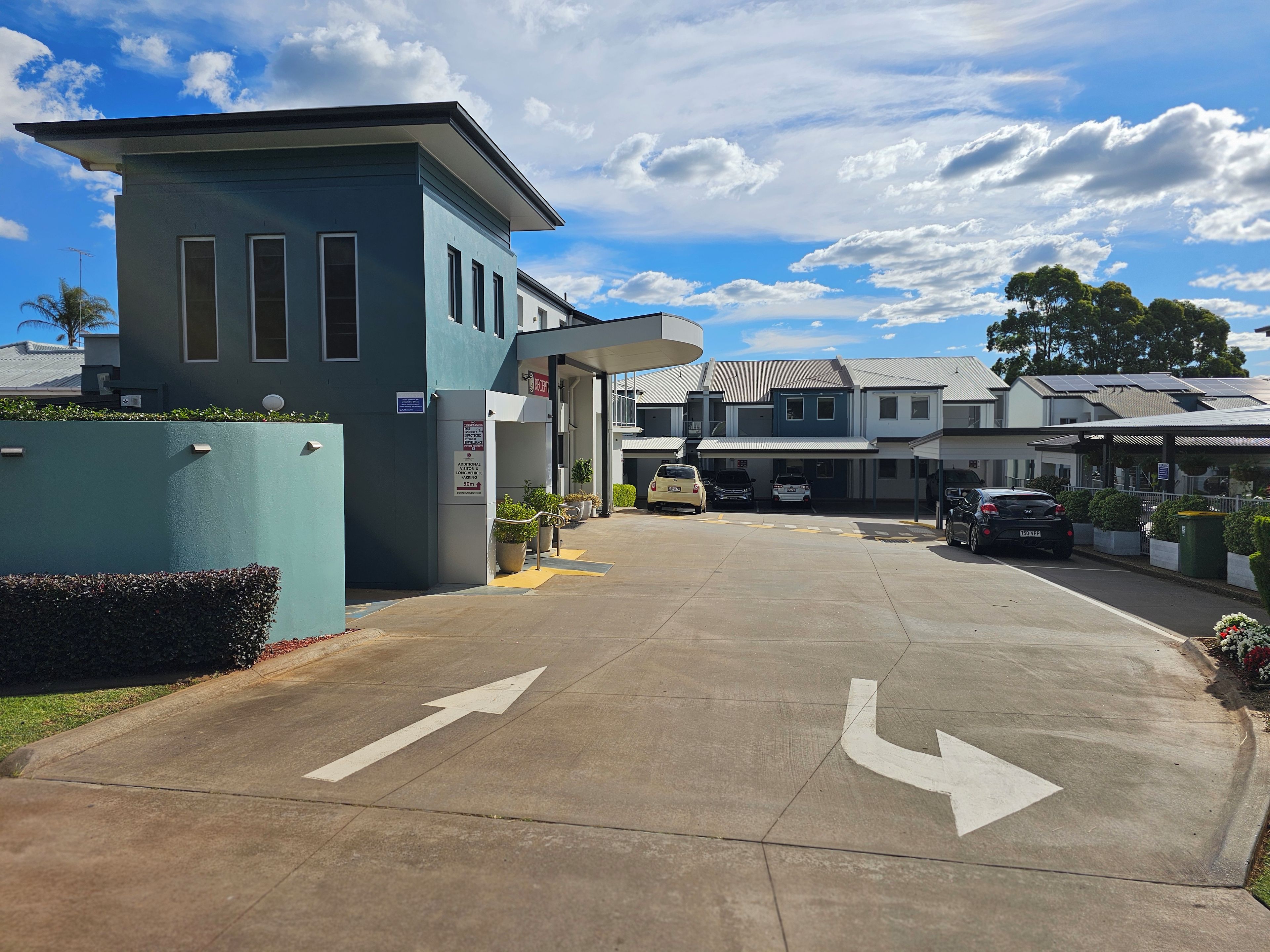 A building entrance with a parking area, directional arrows, and a sign indicating a 50m distance.