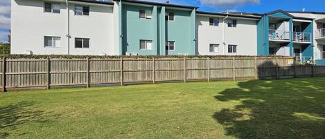A row of modern multi-story residential buildings with a wooden fence in front.