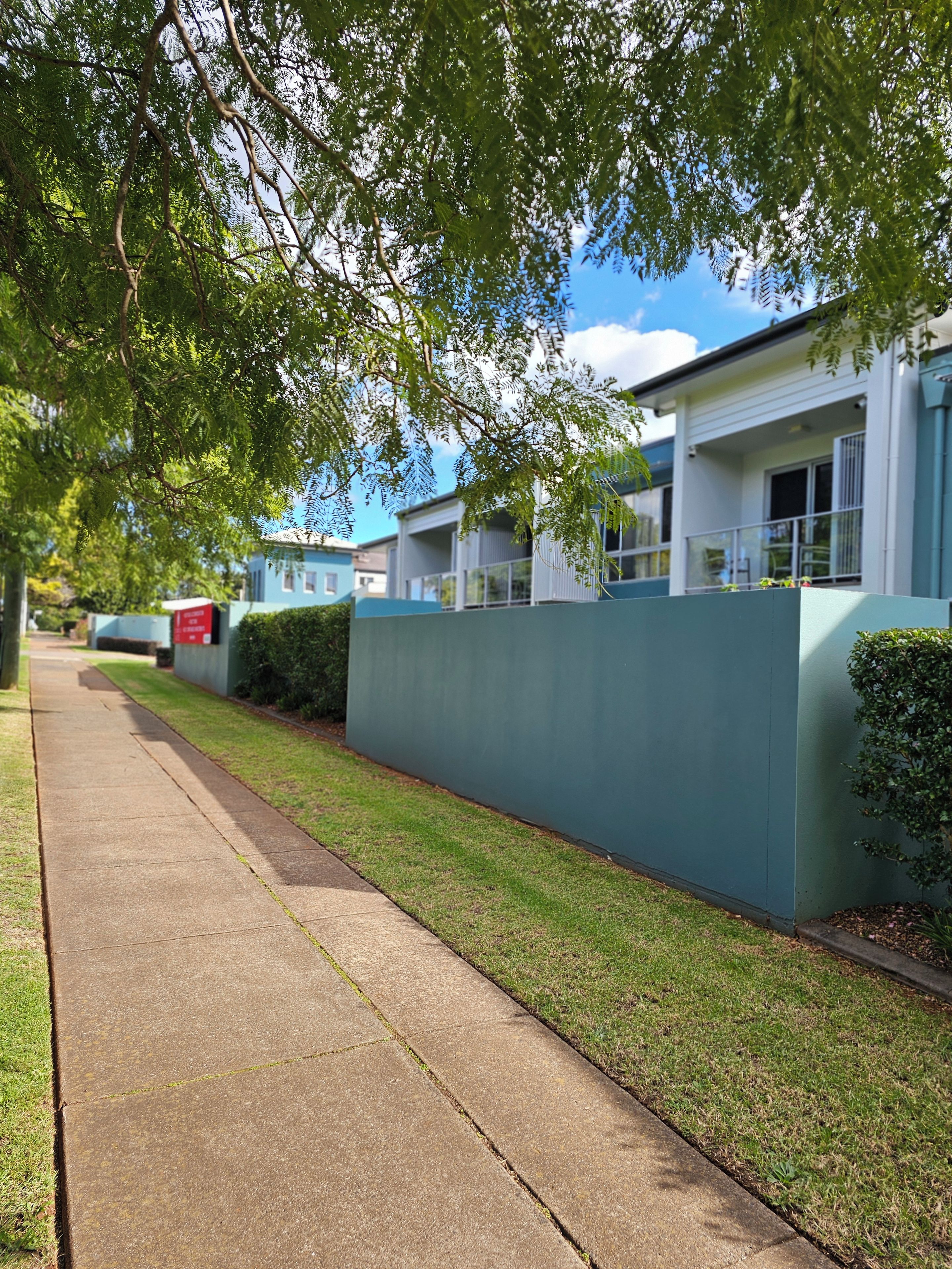 A residential street with houses, a sidewalk, and a clear sky.
