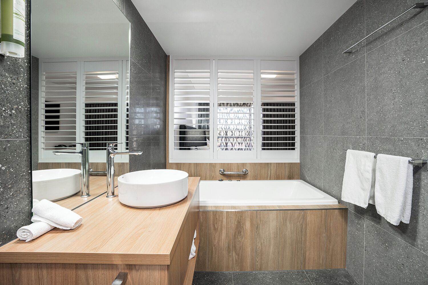 A modern bathroom with a round sink, a bathtub, and a large mirror.