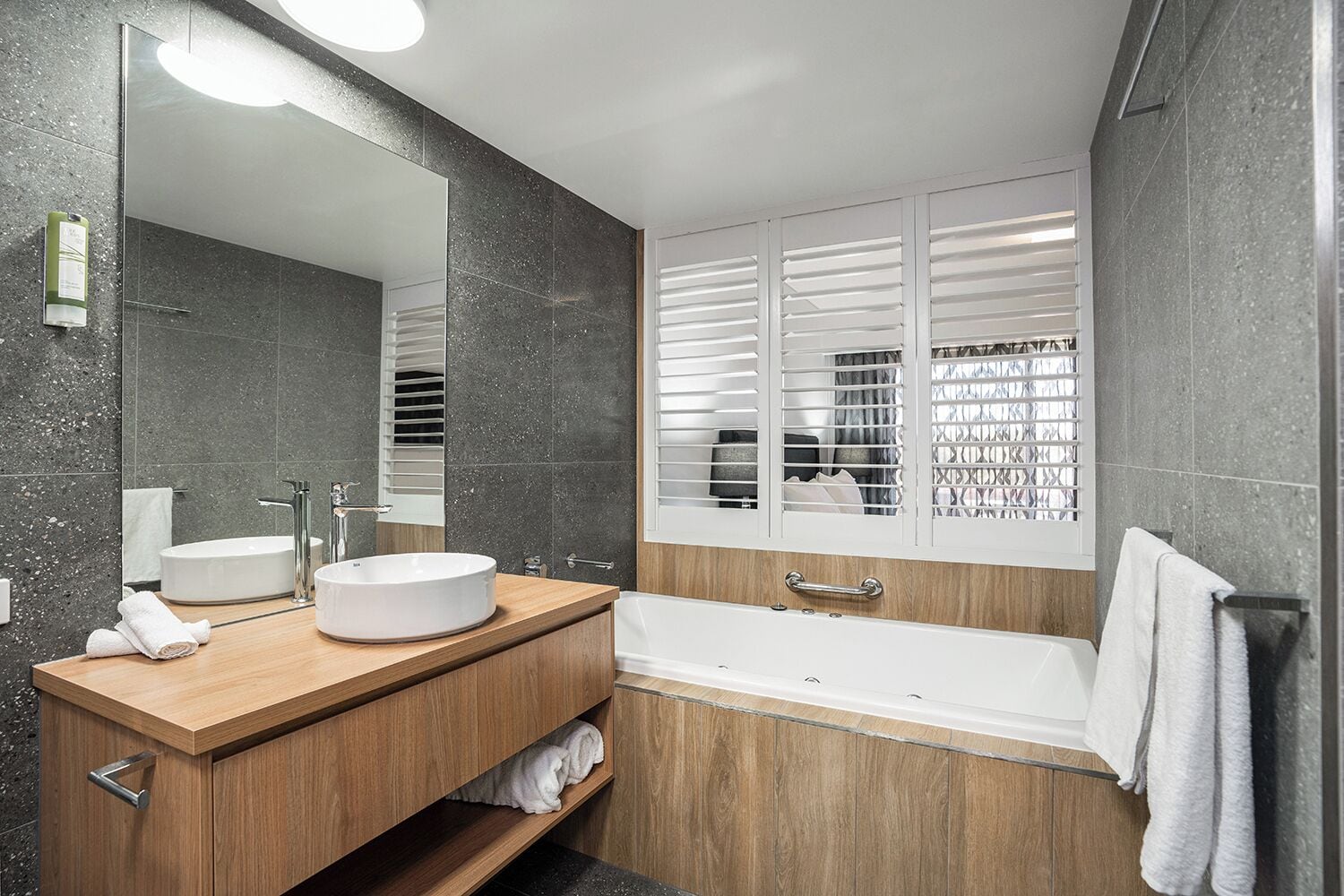 A modern bathroom with a freestanding bathtub, a round sink, and a large mirror.