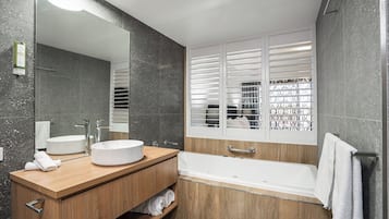 A modern bathroom with a freestanding bathtub, a round sink, and a large mirror.