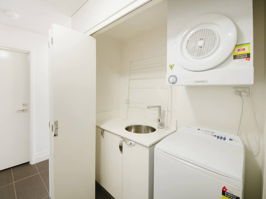 A compact laundry room with a washing machine, a sink, and a door.