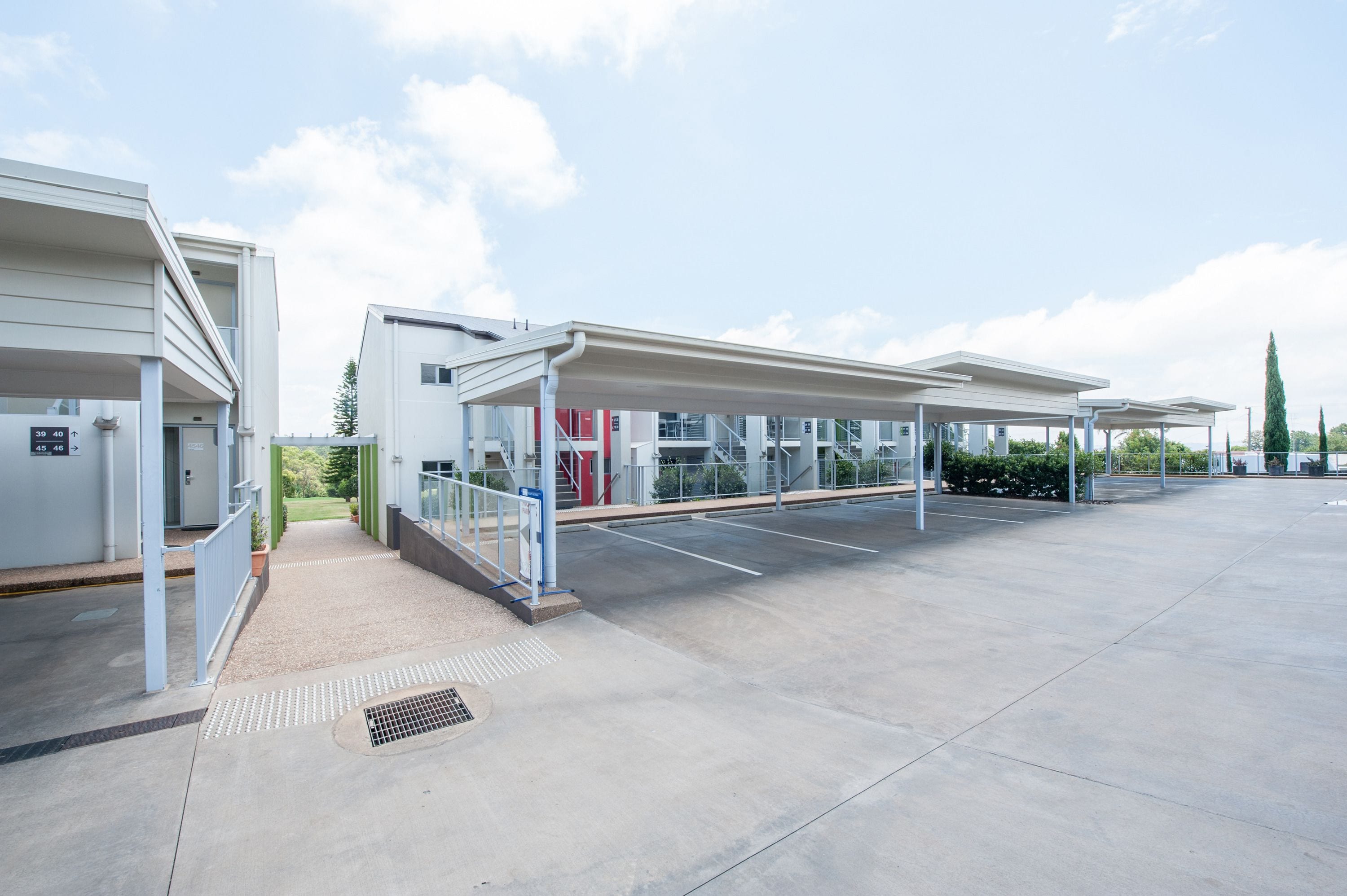 A modern building with covered parking and a clear sky.