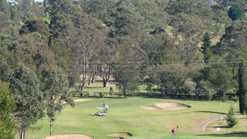 Un campo de golf con búnkeres de arena, árboles y cielo despejado.