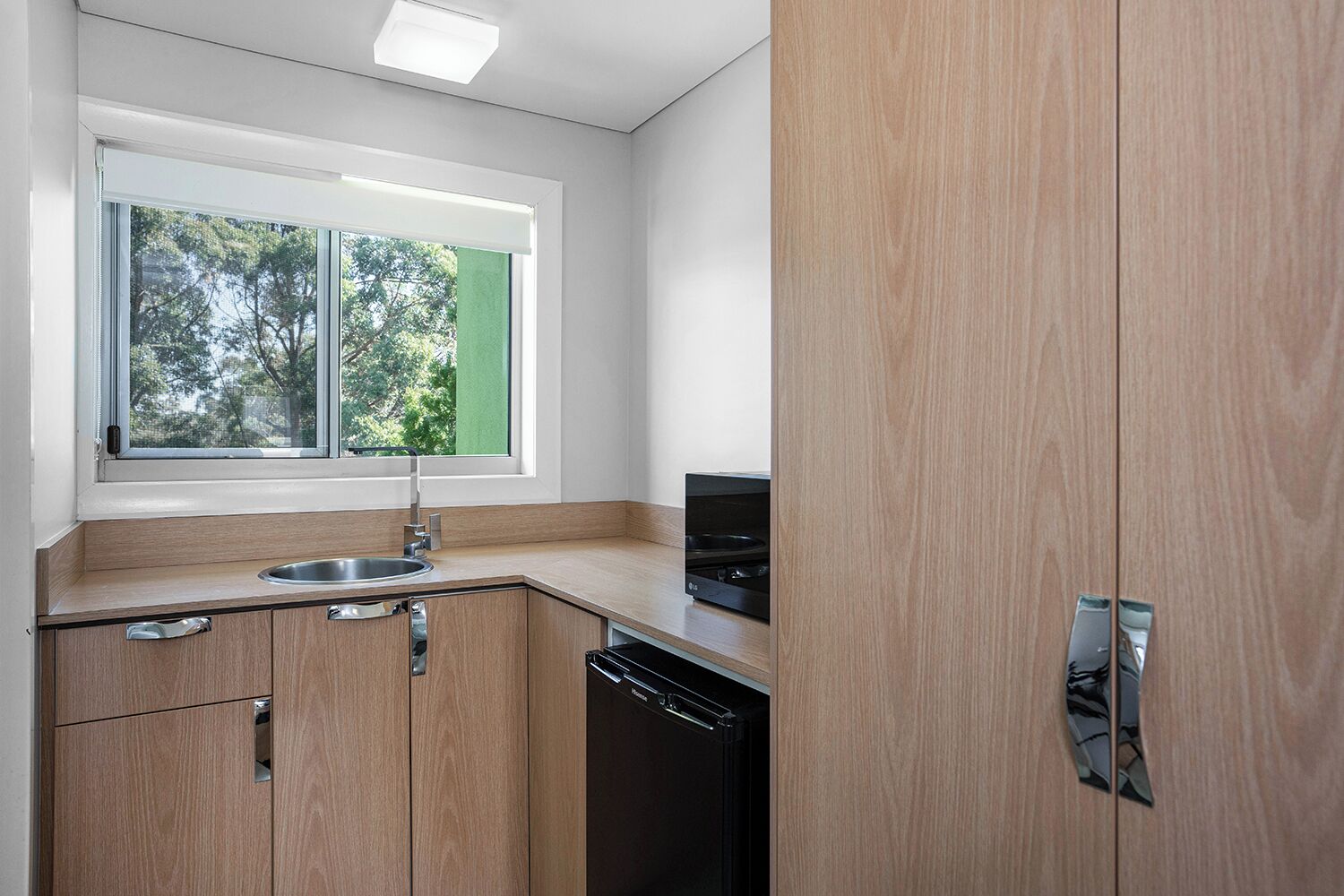 A modern kitchen with wooden cabinets, a stainless steel sink, and a built-in oven.