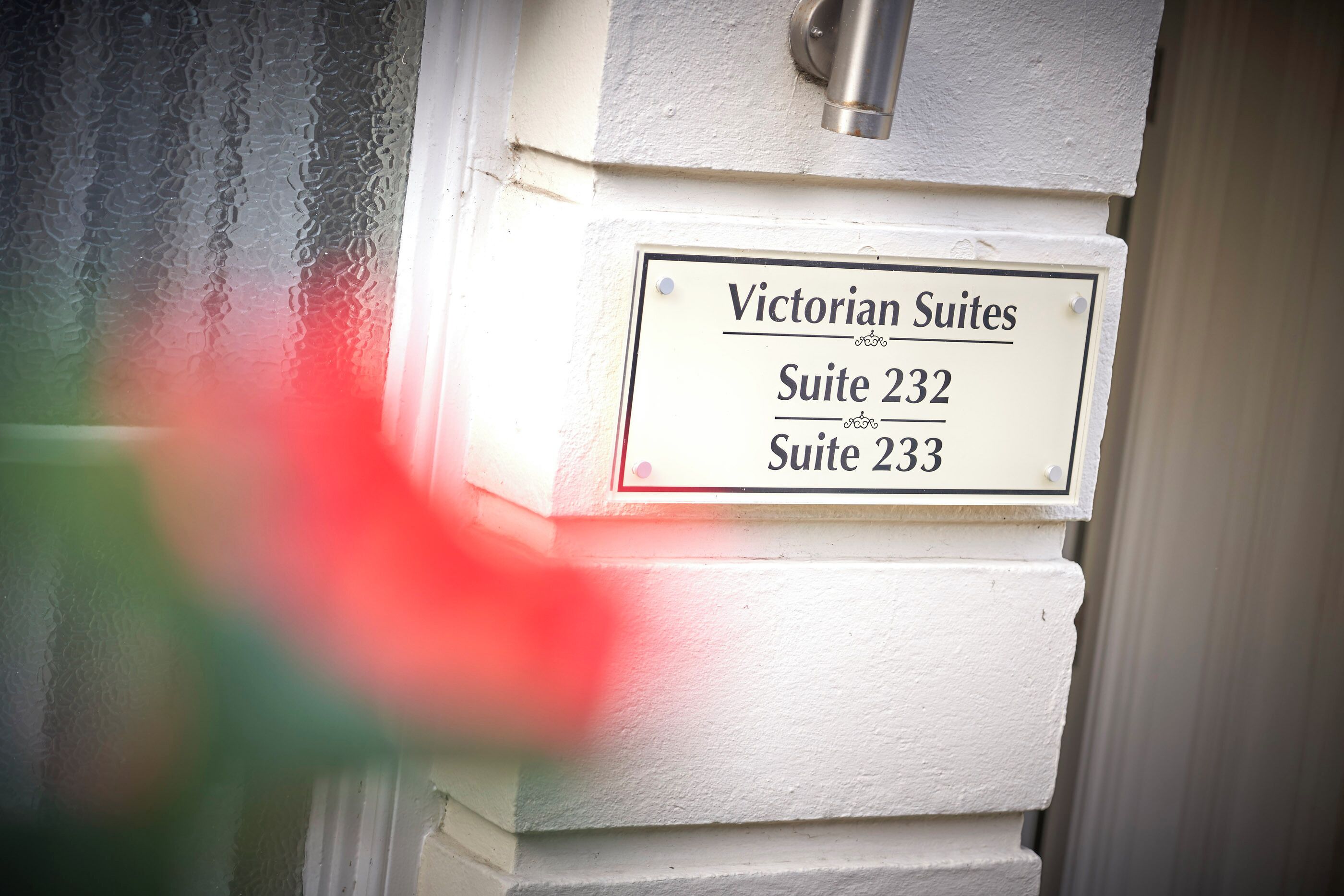 A sign for Victorian Suites, listing Suite 232 and Suite 233.