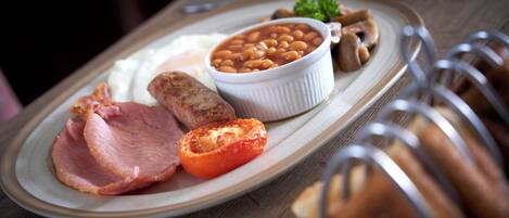 A plate with beans, ham, a tomato, and mushrooms.