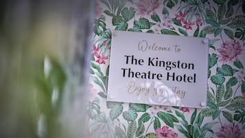 Señal de bienvenida en el Hotel Kingston Theatre, con papel tapiz floral.