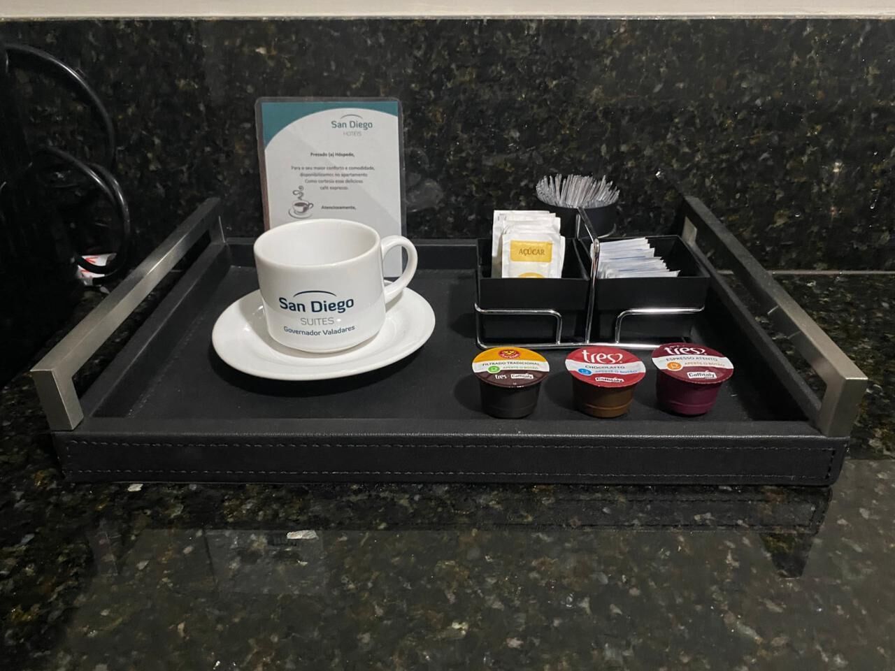 A hotel room tray with a coffee mug, a menu, and three containers of coffee creamer.