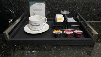 A hotel room tray with a coffee mug, a menu, and three containers of coffee creamer.