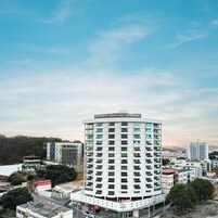 Un hotel de gran altura con fachada curva, varios balcones y un cartel que dice 'San Diego Suites Gov. Valadares'.