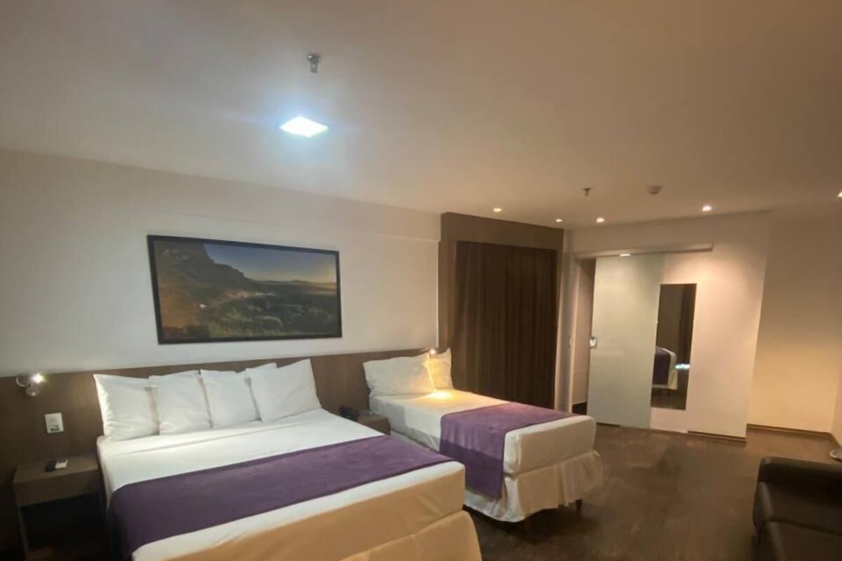 Una habitación de hotel con dos camas, un cuadro grande en la pared y suelo de madera.