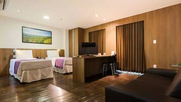 Una habitación de hotel con dos camas, un escritorio, un televisor y un sofá.