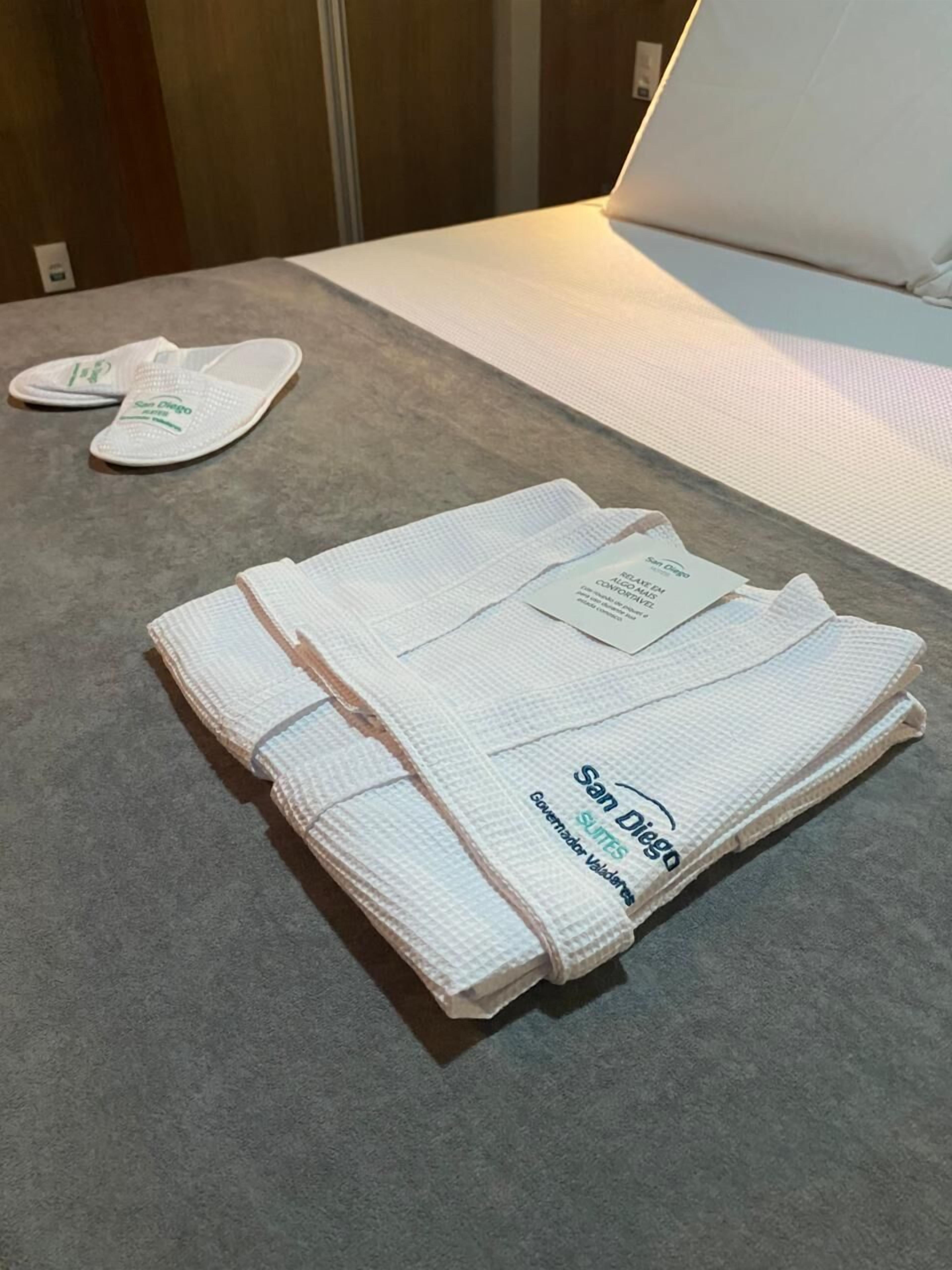 Un joc de tovalloles blanques arrufades amb el logotip 'San Diego' damunt una taula d'habitació d'hotel.