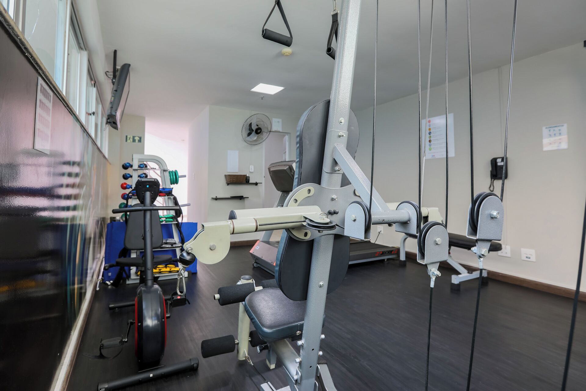 Una palestra con diverse attrezzature per esercizi, tra cui un vogatore e panche per pesi.